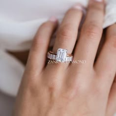 a woman's hand with a diamond ring on her left hand and the other hand holding an engagement ring