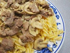 pasta with meat and mushrooms on a blue and white plate