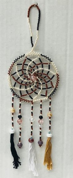 a beaded dream catcher with tassels and beads hanging from it's side