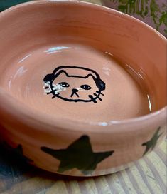 a clay bowl with a drawing of a cat in the center and stars painted on it