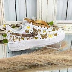 a pair of white sneakers with gold butterflies on them and the words adidas written in gold