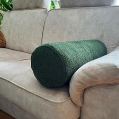 a green pillow sitting on top of a white couch next to a potted plant