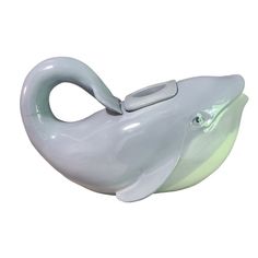 a white dolphin shaped toothbrush holder with a light green bottom and an open mouth