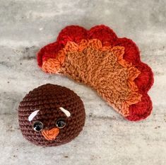 a crocheted turkey hat next to a fake turkey head on the ground with it's eyes wide open