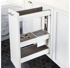 an open cabinet in the corner of a kitchen with marble flooring and white walls