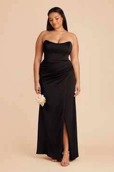 a woman wearing a black strapless dress and holding a white flower in her hand