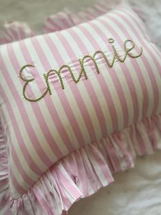 a pink and white striped pillow with the word smile embroidered on it's side