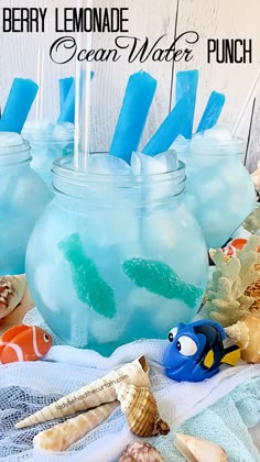 two mason jars filled with blue lemonade and sea water punch are sitting on a towel next to seashells