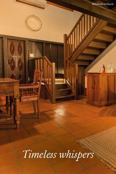 a living room filled with furniture next to a wooden stair case on top of a tiled floor