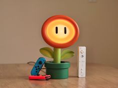 a nintendo wii game controller sitting on top of a wooden table next to a flower