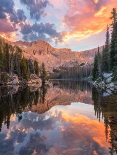 the sun is setting over a mountain lake