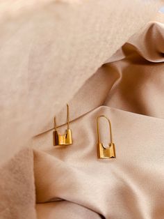 Introducing our captivating and stylish Lock-Shaped Long Earring in stunning shiny gold - a unique accessory that effortlessly merges fashion with a touch of intrigue. Elevate your ensemble with this statement piece that not only adds a dash of sophistication but also reflects your bold and confident style. Crafted with attention to detail, this earring features a meticulously designed lock-shaped charm, cast in radiant gold. The lustrous finish catches and reflects light, ensuring that you'll be the center of attention wherever you go. The elongated design adds a touch of drama, making it perfect for both casual and formal occasions. The secure hook closure ensures a comfortable fit, allowing you to wear this earring with confidence throughout the day or night. The lightweight design ensu Shaped Hoop Earrings, Pad Lock, Long Earring, Confident Style, Earring Sale, Huggie Hoop Earrings, Modern Earrings, Style Earrings, Jewelry Earrings Hoops