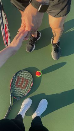 two people standing on a tennis court holding racquets