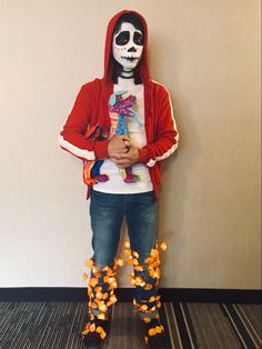 a person in a skeleton mask and hoodie standing next to a wall with flowers on it