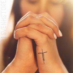 a woman's wrist with a cross tattoo on it