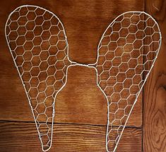 a wire angel wings on a wooden surface