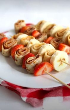 strawberries and banana kabobs on a white plate with red checkered table cloth