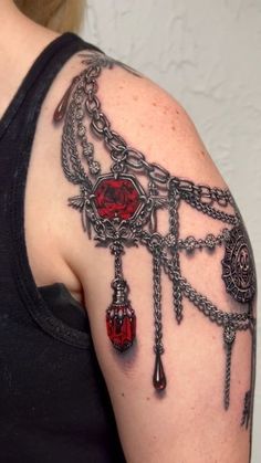 a woman wearing a black shirt has a tattoo on her arm with chains and charms attached to it