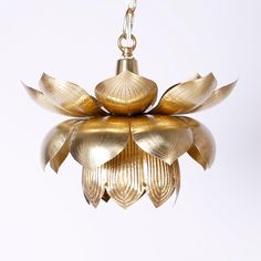 a gold colored chandelier hanging from a metal chain with leaves on the bottom