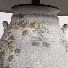 an old vase with moss growing on it and a light fixture in the back ground