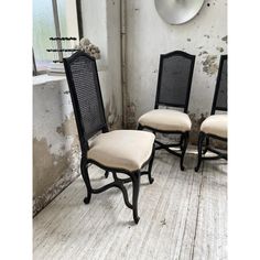 three black chairs with beige cushions sit in front of a mirror on the wall next to a window