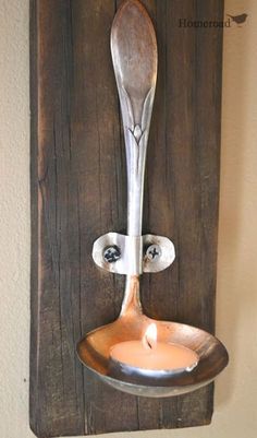 a spoon hanging on a wall with a candle in it