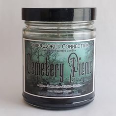 a jar of candle that is sitting on a table next to a white wall with the words cemetery friends written in it