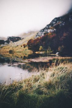 a small lake surrounded by grass and mountains