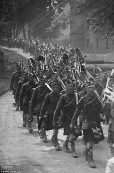 an old black and white photo of soldiers marching down the street