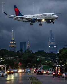 an airplane is flying low over the city at night with traffic on the street below