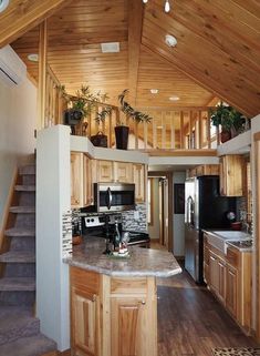 a kitchen with wooden cabinets and stairs leading up to the upper floor