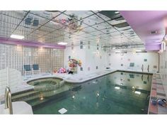 an indoor swimming pool with clear water and colorful tiles on the ceiling, along with lounge chairs