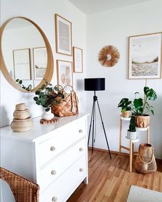 a white dresser topped with lots of potted plants next to a wall mounted mirror