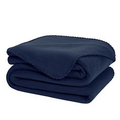 two blankets folded on top of each other in dark blue colors, one with a scalloped edge