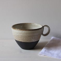 a black and white cup sitting on top of a table next to a napkin with a spoon in it