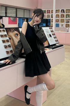 a woman leaning on a counter in front of a display case with eye makeup products