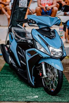 a blue motorcycle parked on top of a grass covered field next to a group of people