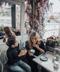 two women sitting at a table drinking coffee