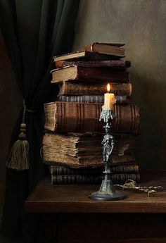 a stack of books sitting on top of a table next to a candle