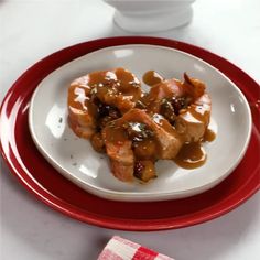 a white plate topped with meat covered in gravy on top of a table