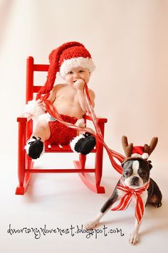 a baby in santa's hat sitting on a rocking chair next to a boston terrier