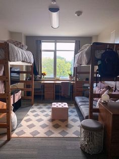 a bedroom with bunk beds and desks in the corner next to a large window