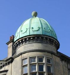 the top of a building with a green dome on it's roof and windows