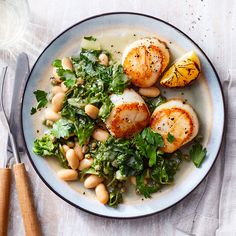 a white plate topped with scallops and greens