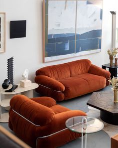 a living room with two couches and a coffee table in front of a painting on the wall