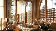 a living room filled with lots of furniture and windows covered in laser cut screens on the walls