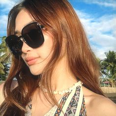 a woman with sunglasses on her head and palm trees in the background