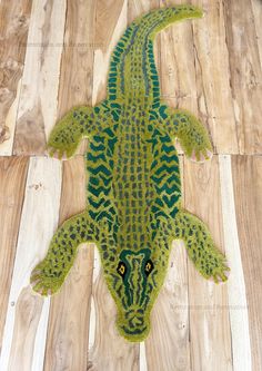 a green and yellow rug with an alligator on it's back laying on wooden floor