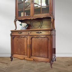 an old wooden china cabinet with glass doors