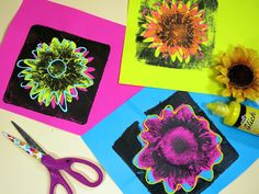 four different colored papers with flowers on them and scissors next to one another near a yellow sunflower